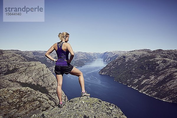 Junge Frau genießt den Blick über den Fjord vom Gipfel des Preikestolen  Rogaland  Norwegen  Europa