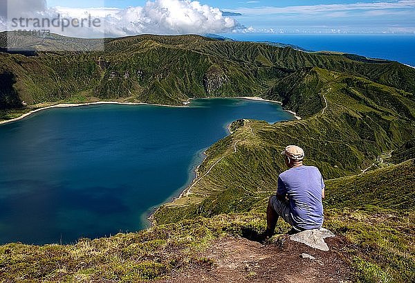 Mann sitzt auf einem Stein und schaut auf den See  Lagoa Fogo  Feuerlagune  Insel São Miguel  Azoren  Portugal  Europa