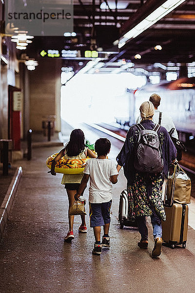 Familie in voller Länge mit Gepäck auf dem Bahnsteig am Bahnhof