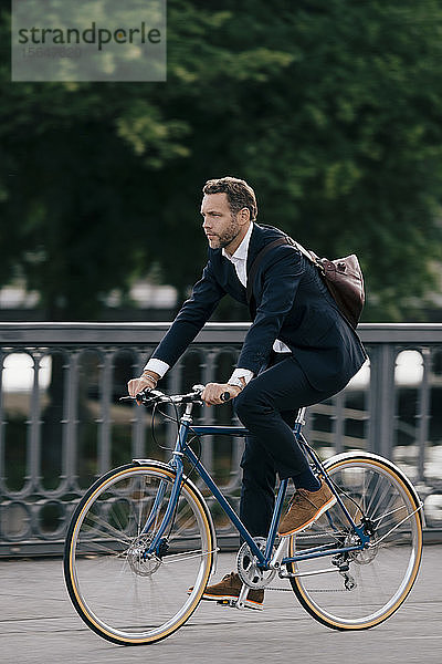 Selbstbewusster Geschäftsmann in voller Länge mit dem Fahrrad auf der Straße in der Stadt