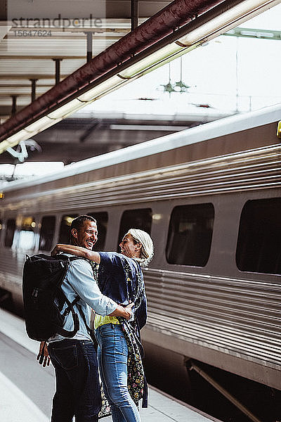 Glückliches Paar umarmt sich mit dem Zug am Bahnhof