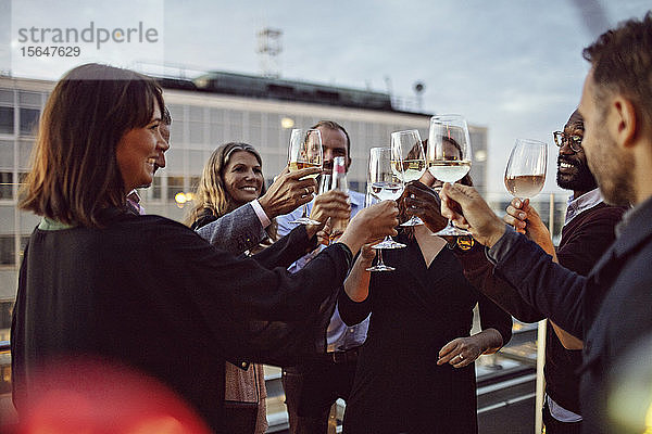 Geschäftskollegen stoßen auf Weingläser an  während sie im Büro feiern - Party auf der Terrasse