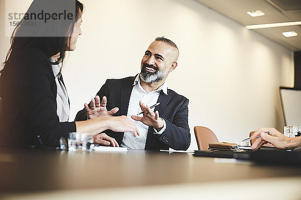 Männliche und weibliche Anwälte diskutieren am Konferenztisch im Sitzungssaal