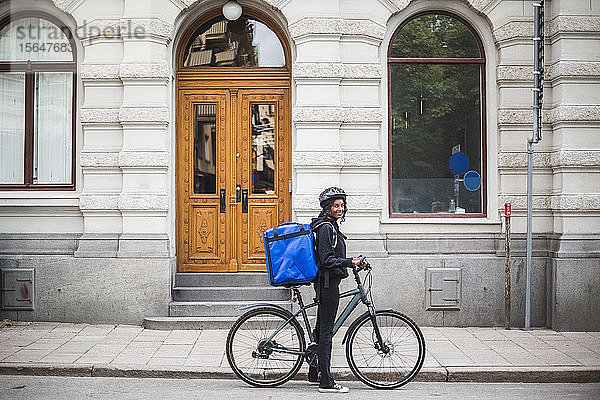 Seitenansicht Porträt einer lächelnden Lieferfrau mit Fahrrad auf der Straße in der Stadt