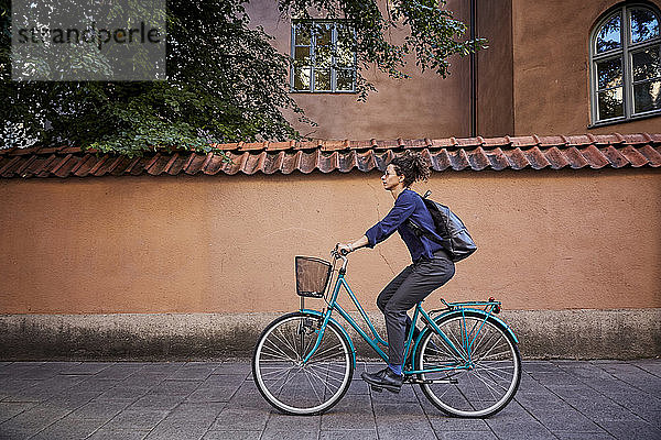 Seitenansicht einer Architektin  die auf der Straße in der Stadt Fahrrad fährt