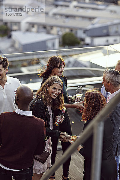 Fröhliche Begrüßung von Fachleuten bei einer Party auf der Terrasse nach Feierabend