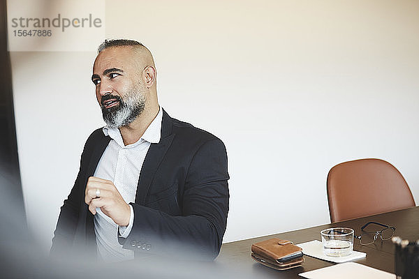 Selbstbewusster männlicher Anwalt spricht  während er im Sitzungssaal auf den Konferenztisch schaut