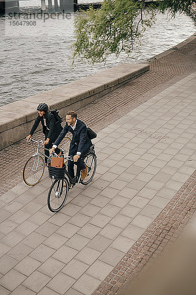 Hochwinkelansicht eines Geschäftsmannes und einer Geschäftsfrau  die auf einem Fußweg in der Stadt Fahrrad fahren