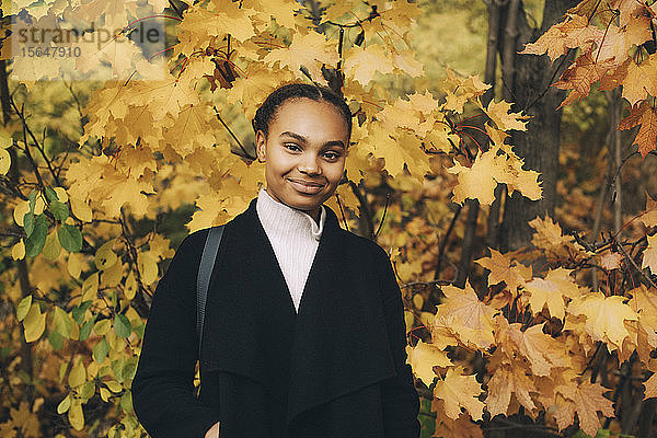 Porträt einer selbstbewussten Teenagerin  die vor Orangenbäumen steht