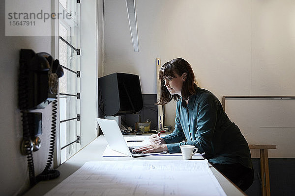 Selbstbewusste Architektin mit Laptop im Büro