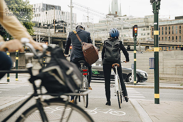 Rückansicht eines Geschäftsmannes und einer Geschäftsfrau mit Fahrrädern auf der Straße in der Stadt