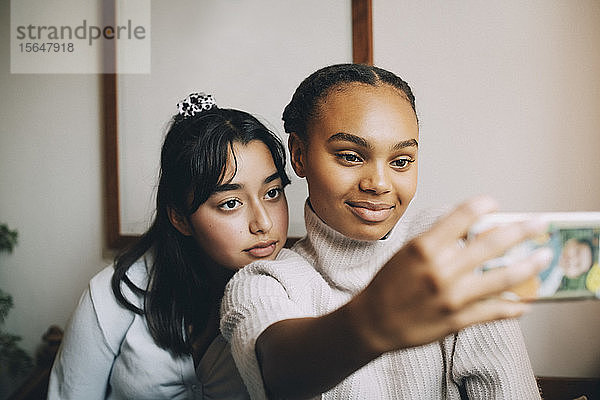 Mädchen im Teenageralter beim Selbermachen mit dem Smartphone zu Hause