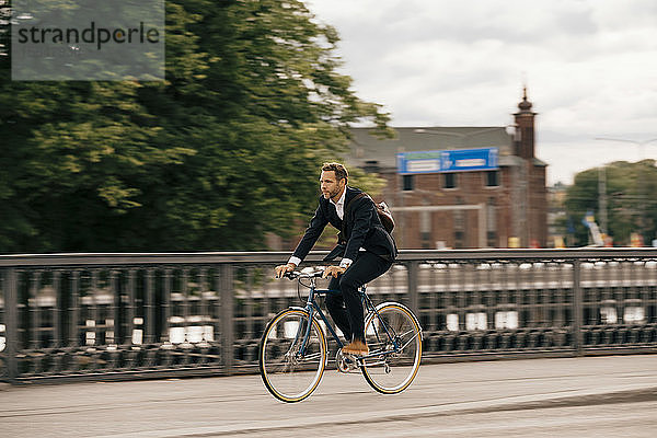 Selbstbewusster Geschäftsmann in voller Länge mit dem Fahrrad auf der Straße in der Stadt