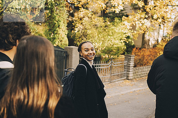 Lächelndes Teenager-Mädchen mit Freunden auf der Straße in der Stadt