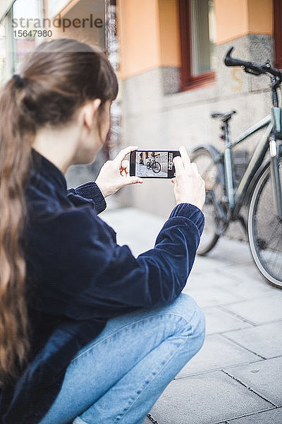 Junge Frau fotografiert Fahrrad auf Wanderweg