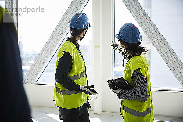 Seitenansicht von Ingenieurinnen  die auf der Baustelle diskutieren