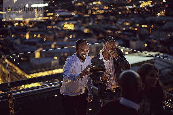 Glückliche Profis  die sich mit einem Smartphone auf einer Terrasse in der Stadt selbstständig machen