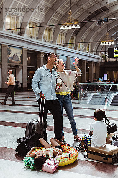 Gelangweilte Familie mit Gepäck wartet am Bahnhof