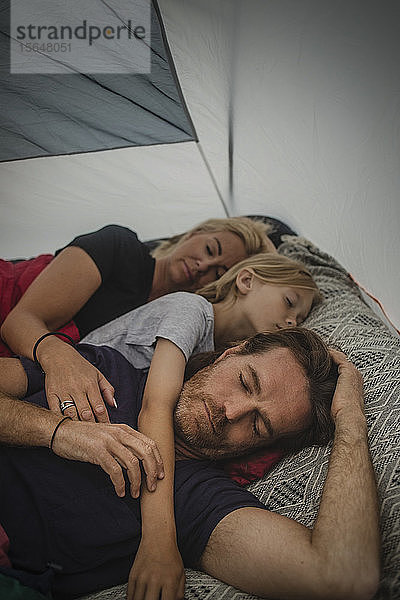 Familie schläft beim Camping mit geschlossenen Augen im Zelt