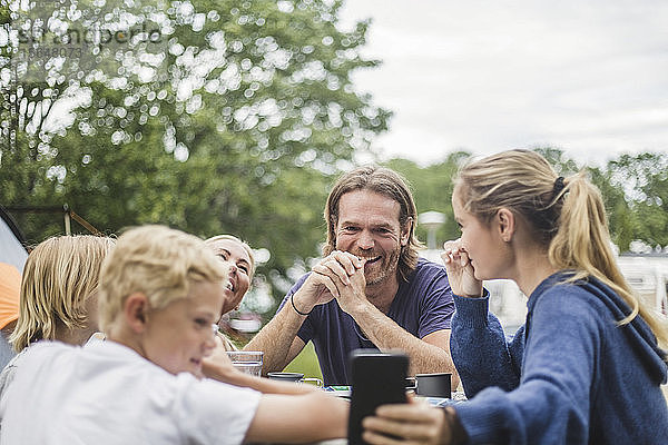 Teenager-Mädchen nimmt Selfie mit der Familie auf dem Tisch auf dem Campingplatz