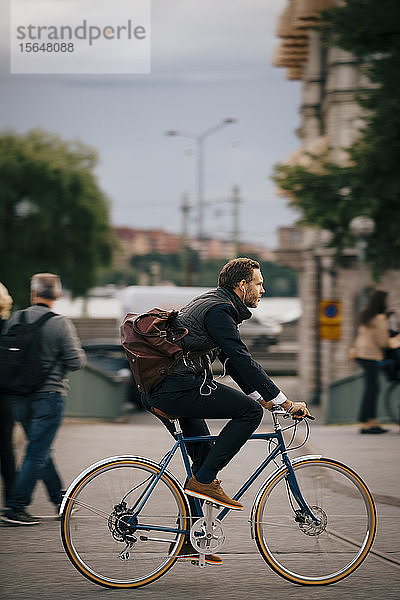 Seitenansicht eines selbstbewussten Geschäftsmannes  der auf der Straße in der Stadt Fahrrad fährt