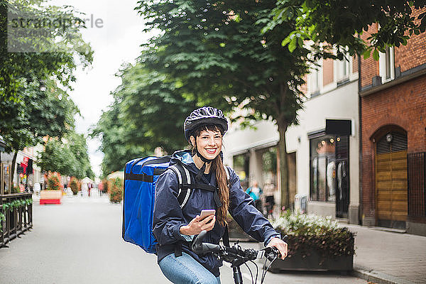 Porträt einer lächelnden Essenslieferantin mit Fahrrad auf der Straße