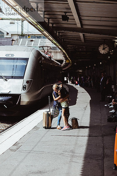 Glückliche Mutter und Tochter umarmen sich bei der Begrüßung am Bahnhof