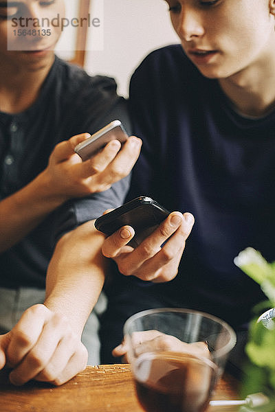 Ein Teil der männlichen Teenager benutzt Mobiltelefone  während sie zu Hause zusammen sitzen