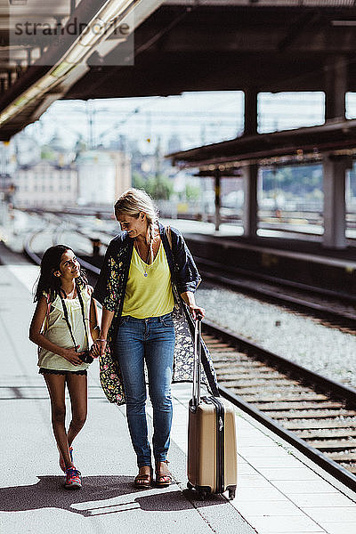 Mutter und Tochter in voller Länge mit Gepäck zu Fuß am Bahnhof