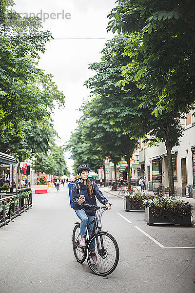 Essenslieferantin mit Fahrrad auf der Straße in der Stadt
