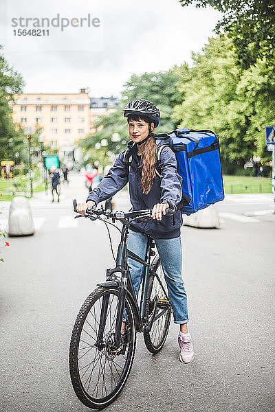 Porträt einer selbstbewussten Essenslieferantin mit Fahrrad auf der Straße in der Stadt