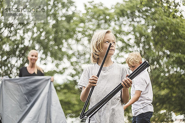 Mädchen mit Stangen  das der Familie beim Zeltaufbau auf dem Campingplatz hilft