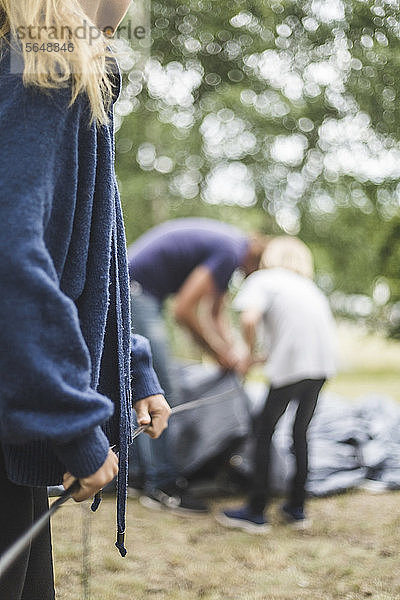 Teenager-Mädchen hilft der Familie beim Zeltaufbau auf dem Campingplatz