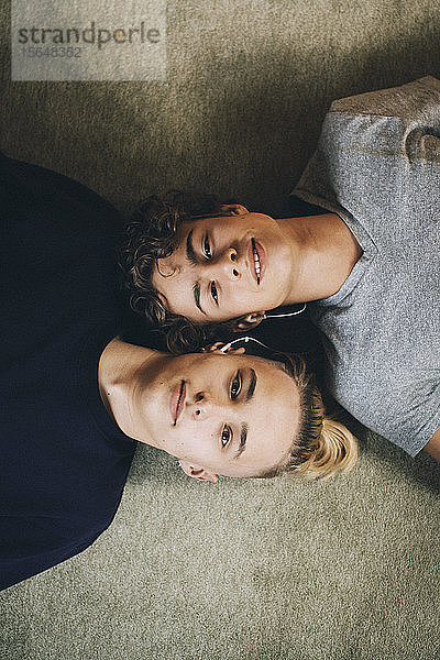 Direkt darüber Porträt von Teenager-Jungen  die zu Hause zusammen auf einem Teppich liegen