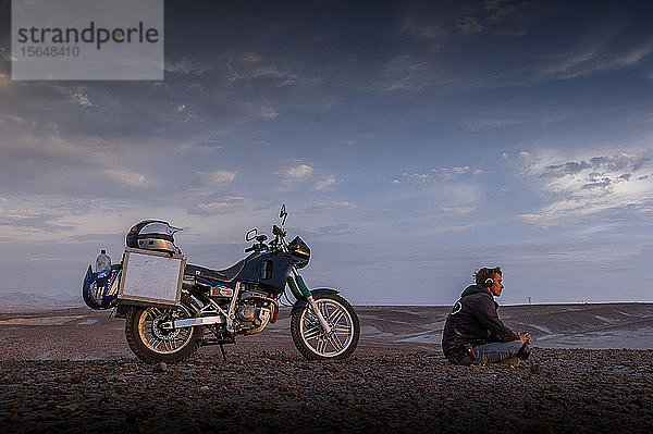 Motorradfahrer mit Kopfhörern geniesst Frieden in der Wüste  Arequipa  Peru