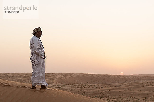 Omanischer Mann steht auf Sanddünen  Wüste Wahiba Sands  Oman