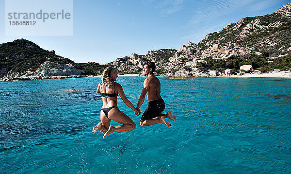Junges Paar springt von einer Yacht ins Meer  Insel La Maddalena  Sardinien  Italien