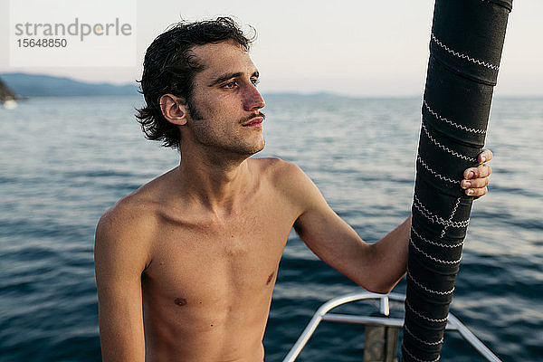 Junger Mann auf Segelboot schaut in die Ferne  Italien