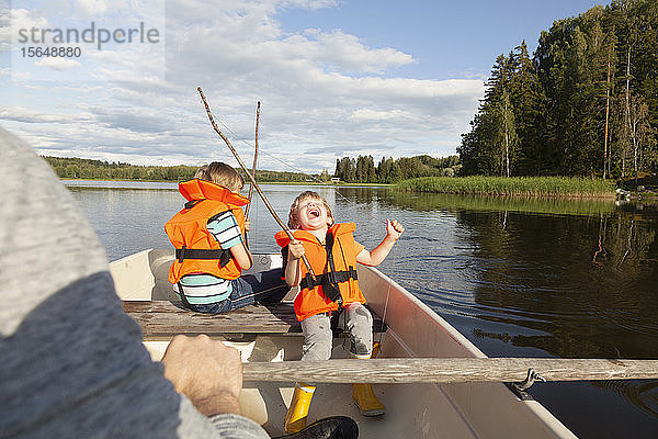 Erwachsener segelt mit aufgeregten Jungen auf einem Boot auf dem See  Finnland