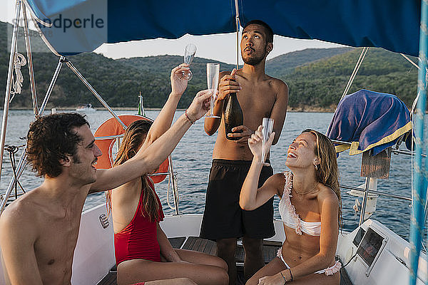 Freunde stoßen mit Champagner auf einem Segelboot an  Italien