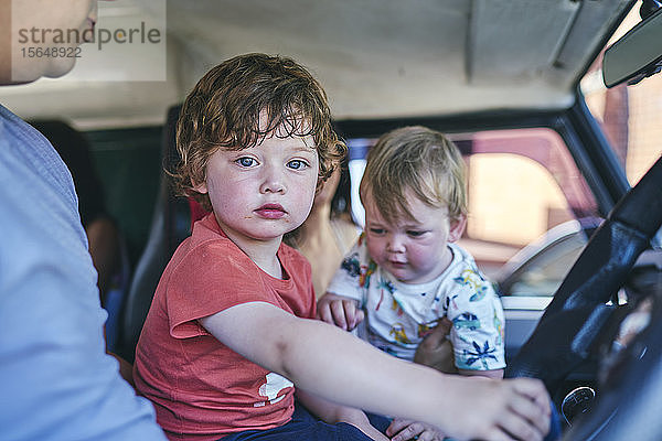 Junge und kleine Schwester sitzen mit dem Vater im Auto