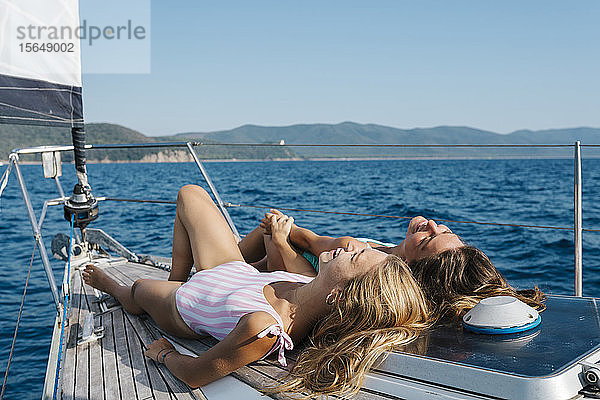 Freunde beim Sonnenbaden an Deck eines Segelbootes  Italien