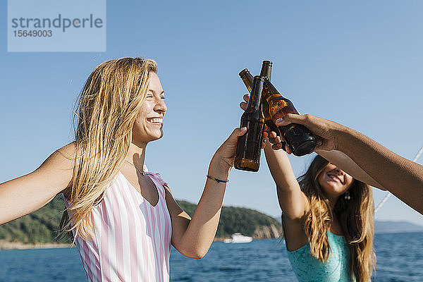 Freunde stoßen mit Bier auf dem Segelboot an  Italien