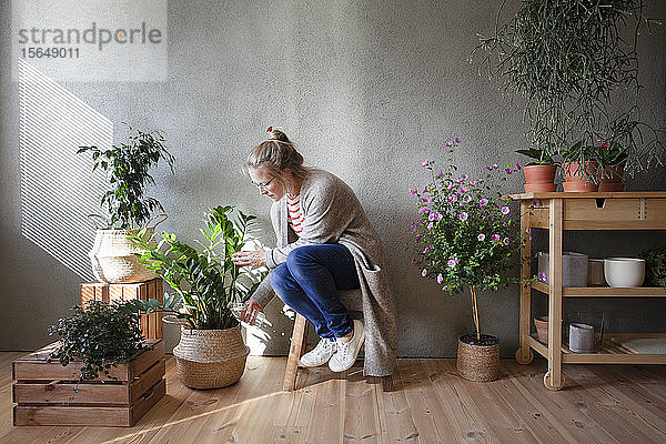 Frau kümmert sich um Topfpflanzen im Innengarten