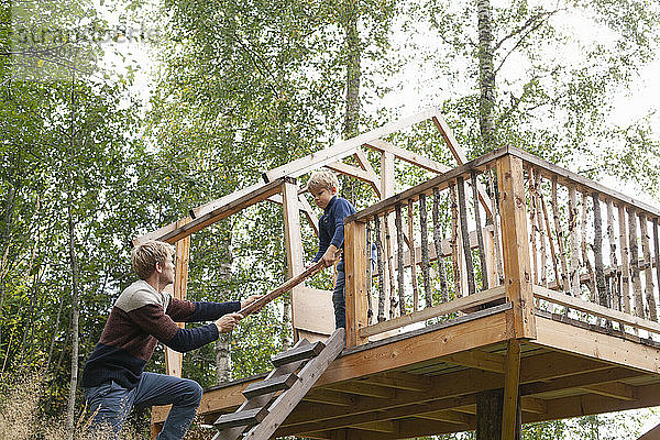 Vater und Sohn bauen gemeinsam Baumhaus im Garten