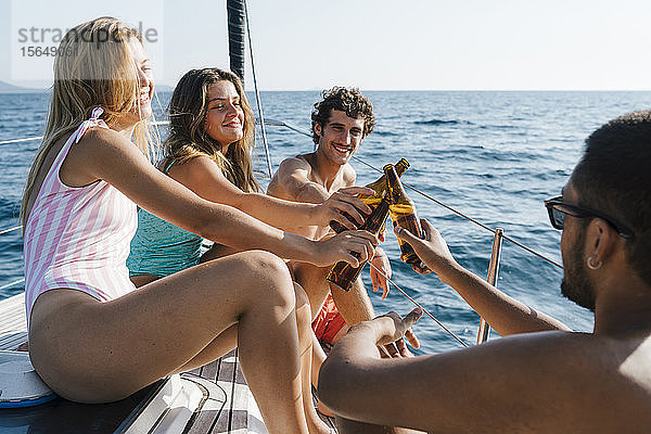 Freunde stoßen mit Bier auf dem Segelboot an  Italien