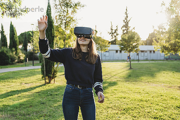 Junge Frau schaut durch VR-Headset im Park