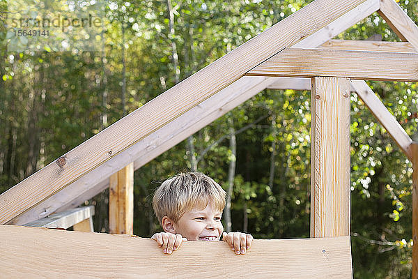 Junge schaut aus unfertigem Baumhaus