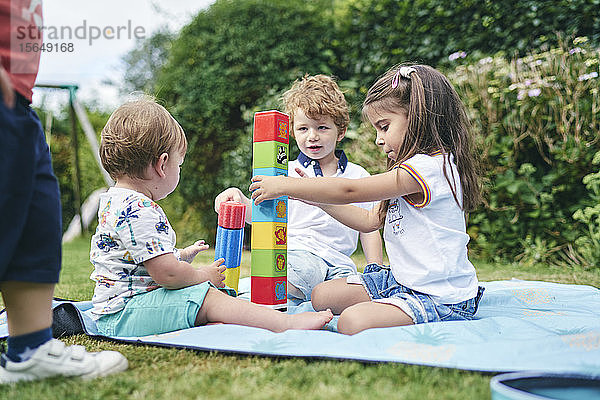 Brüder und Schwestern spielen mit Blöcken auf einer Picknickdecke