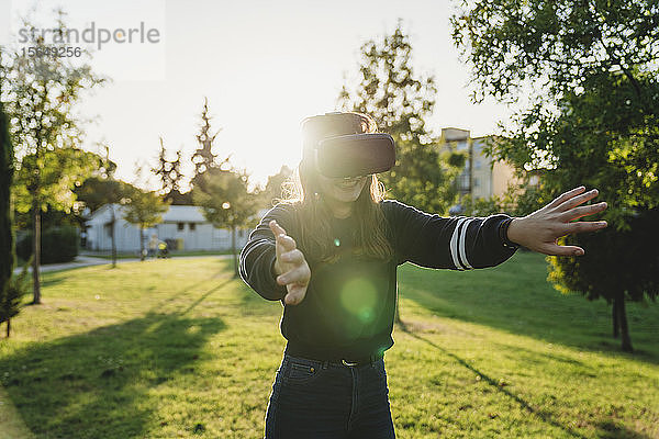 Junge Frau schaut durch VR-Headset im Park